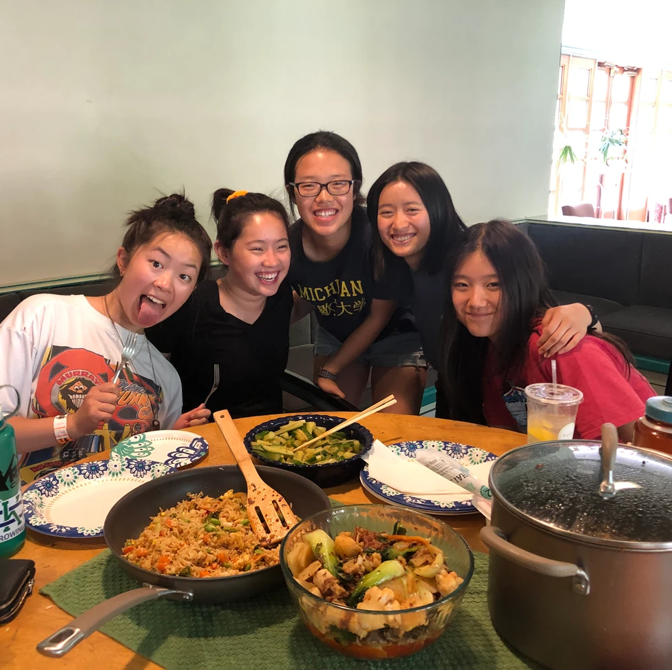 People in front of a table with chinese dishes.