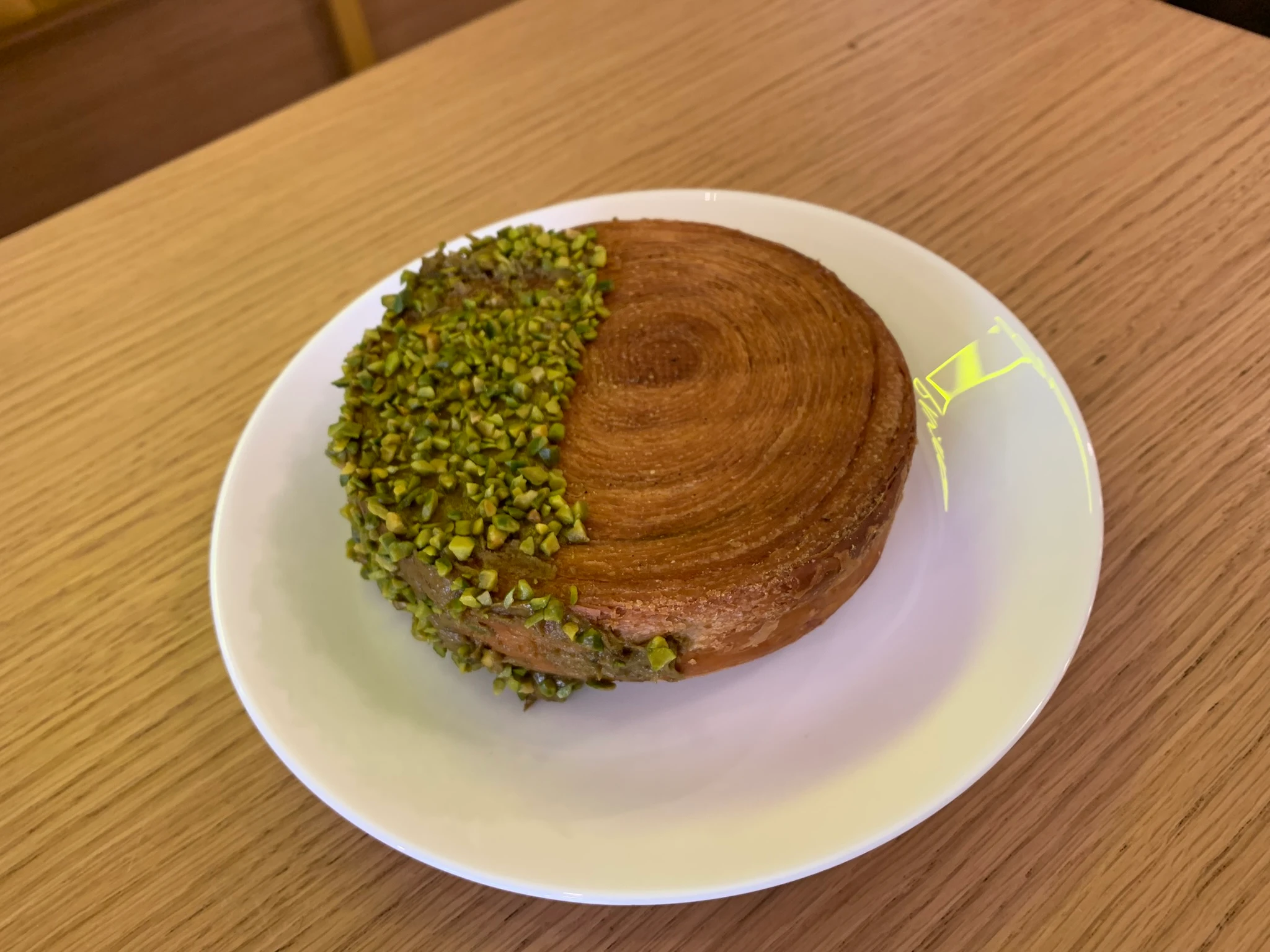 Pinwheel croissant dipped in pistachio cream.