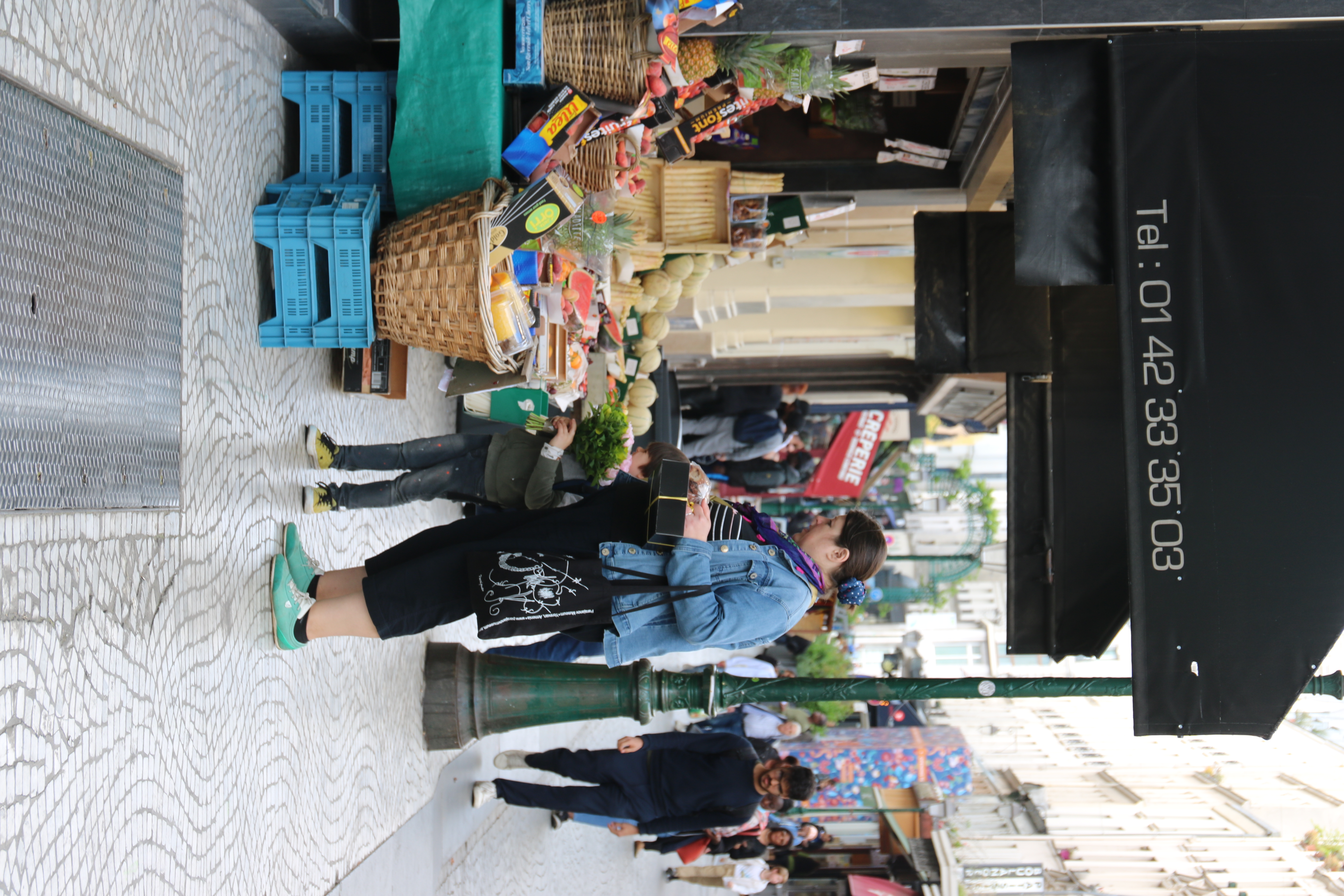 A mother and child shopping for groceries from a streetside vendor.