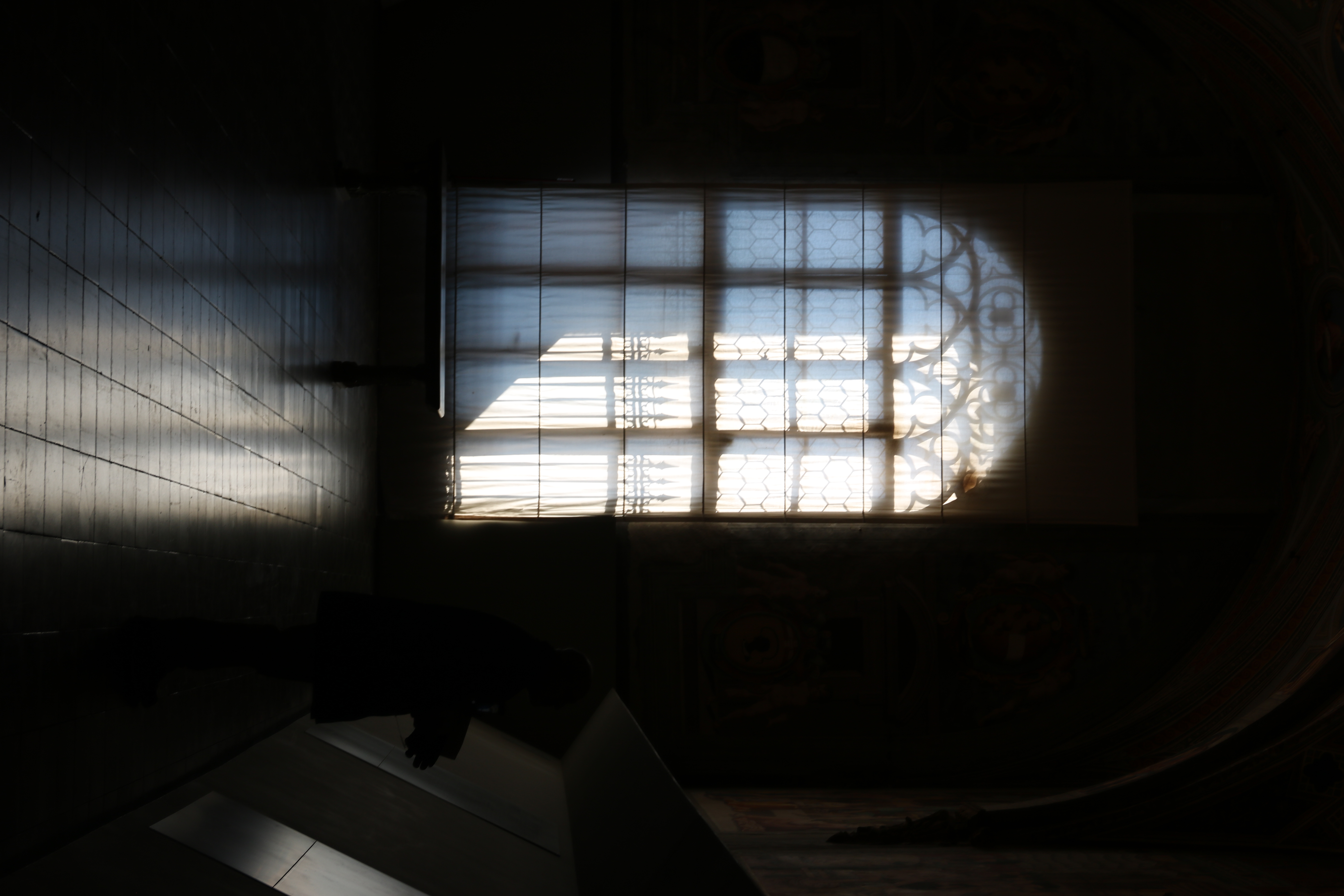 Daylight streaming through the windows, highlighting the outlines of the elaborate window frame.